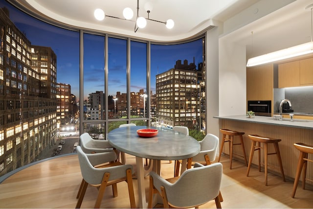 dining space featuring light wood-style floors, a view of city, and floor to ceiling windows