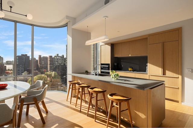 kitchen with modern cabinets, a peninsula, expansive windows, a city view, and light wood-style floors