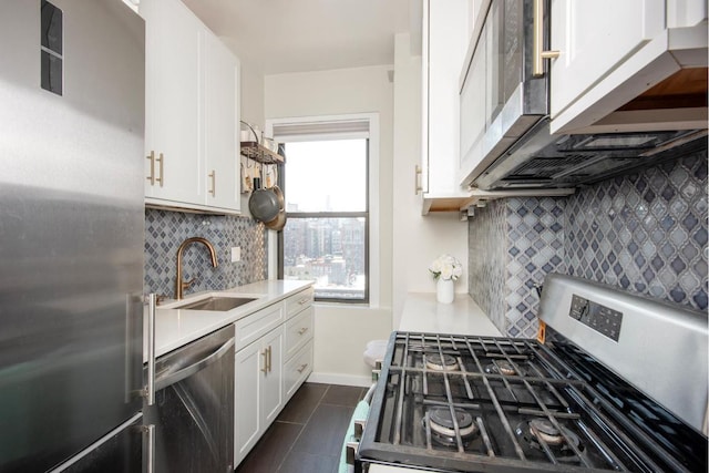 kitchen featuring sink, dark tile patterned floors, appliances with stainless steel finishes, white cabinetry, and backsplash