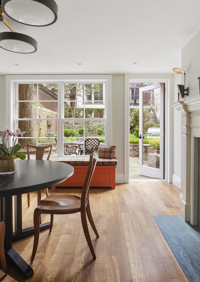 dining room with baseboards, a fireplace with flush hearth, and light wood-style floors