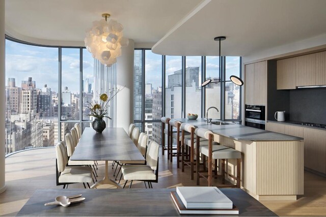 dining space with a healthy amount of sunlight, light wood-type flooring, sink, and floor to ceiling windows