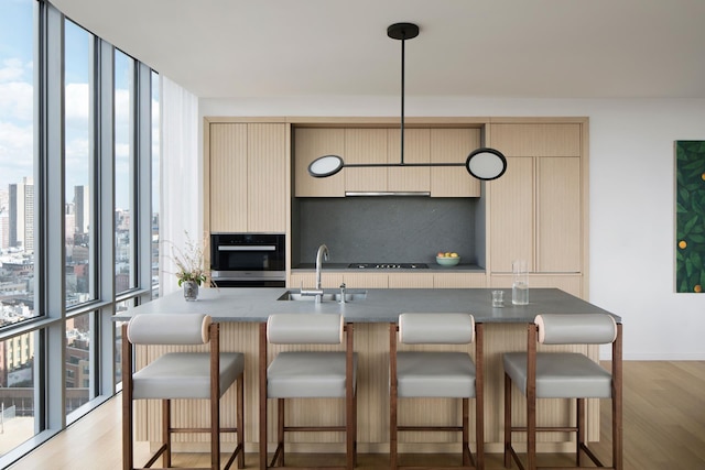 kitchen featuring cream cabinetry, backsplash, a wall of windows, and oven