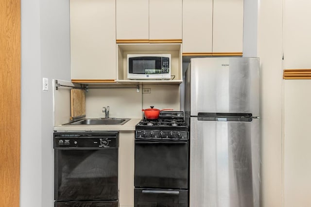 kitchen featuring sink, white cabinets, and black appliances