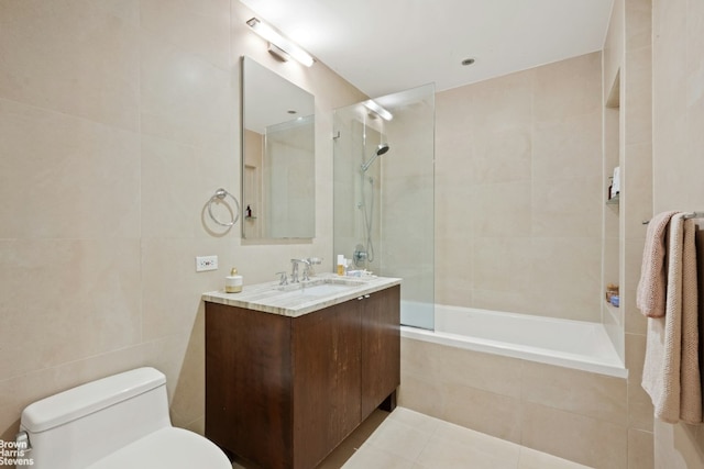 full bathroom with tiled shower / bath combo, tile patterned flooring, vanity, tile walls, and toilet