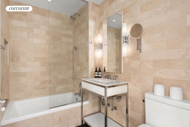 full bathroom featuring enclosed tub / shower combo, toilet, sink, and tile walls