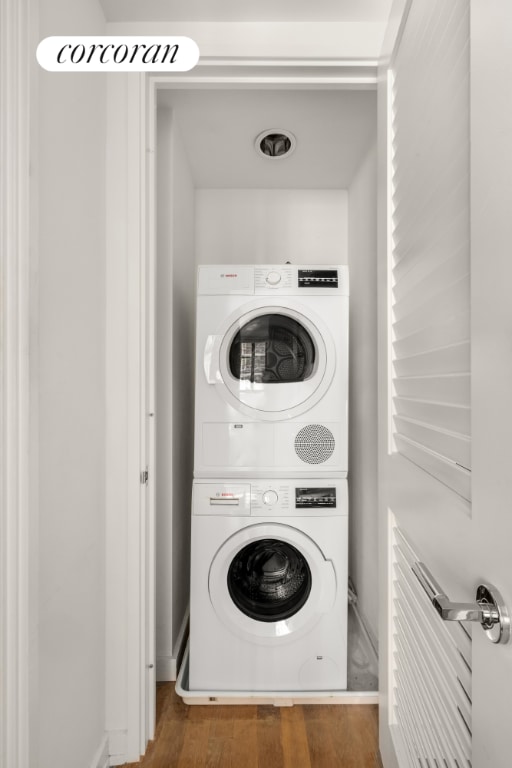 laundry room featuring wood-type flooring and stacked washer and clothes dryer