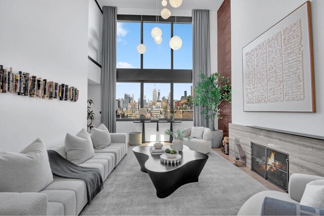 living area with a view of city, plenty of natural light, a glass covered fireplace, and a towering ceiling