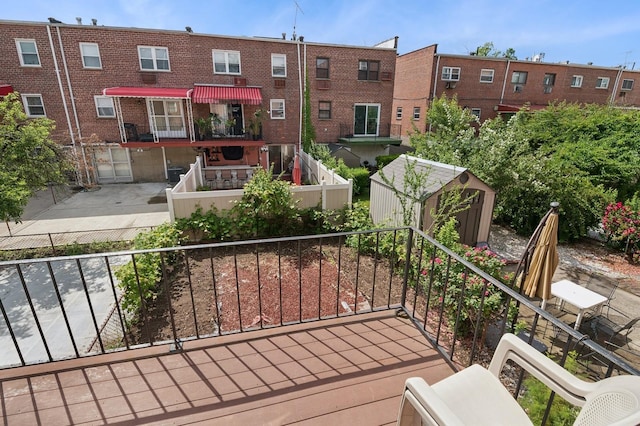 wooden deck with an AC wall unit, a storage shed, an outdoor structure, and fence