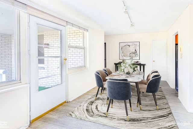 dining space with rail lighting and light hardwood / wood-style flooring