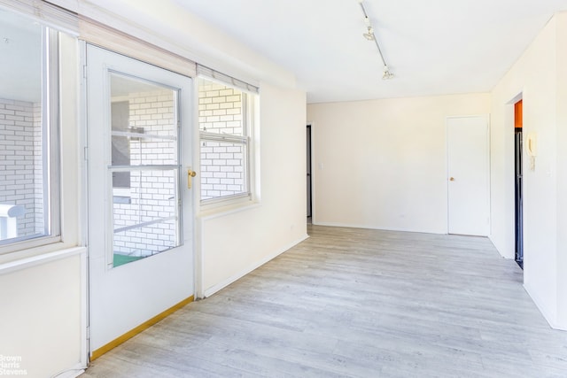 spare room with baseboards, wood finished floors, and track lighting