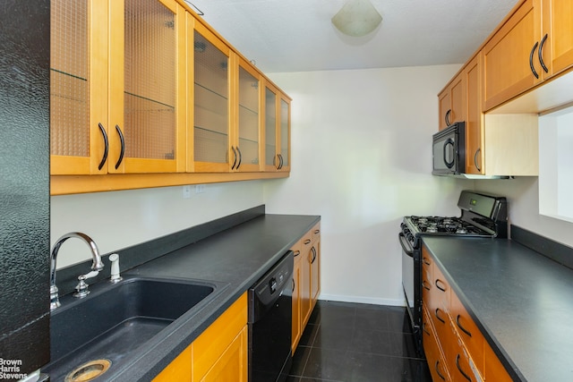 kitchen featuring glass insert cabinets, dark countertops, a sink, and black appliances