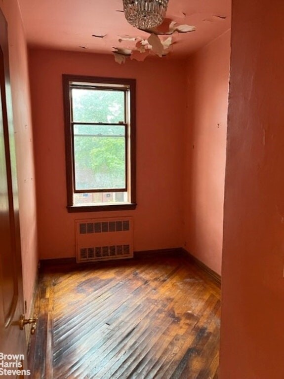 empty room with wood-type flooring and radiator