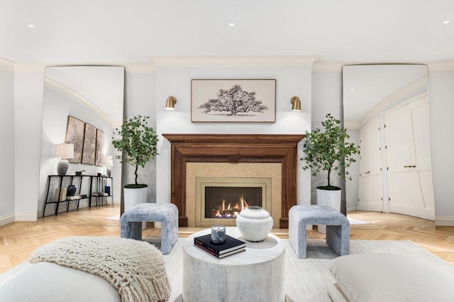 living area with a high end fireplace, ornamental molding, and light parquet floors