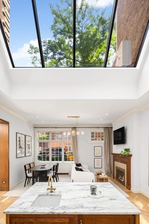 kitchen with sink, a towering ceiling, light stone countertops, and hanging light fixtures