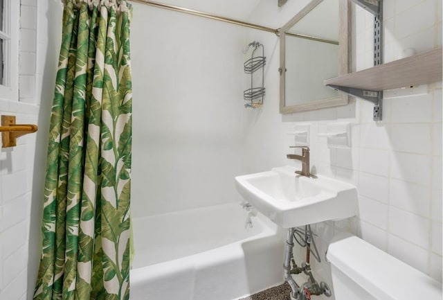 full bathroom featuring toilet, tasteful backsplash, shower / bath combination with curtain, tile walls, and sink