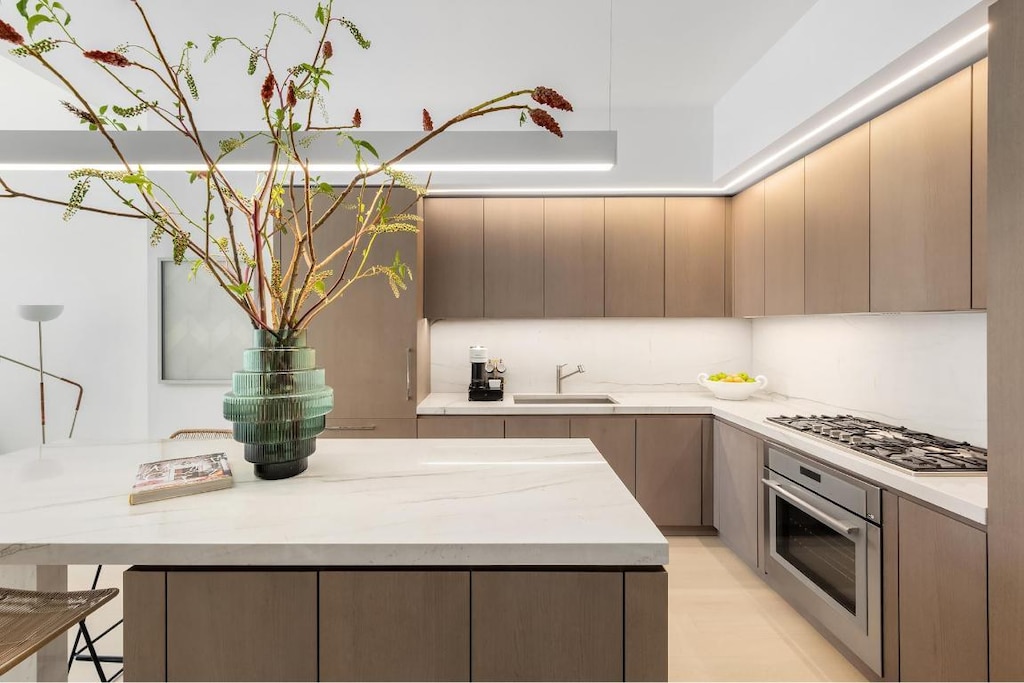 kitchen with appliances with stainless steel finishes, light stone counters, and sink