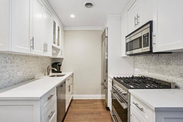 kitchen with visible vents, dark wood-type flooring, a sink, premium appliances, and light countertops