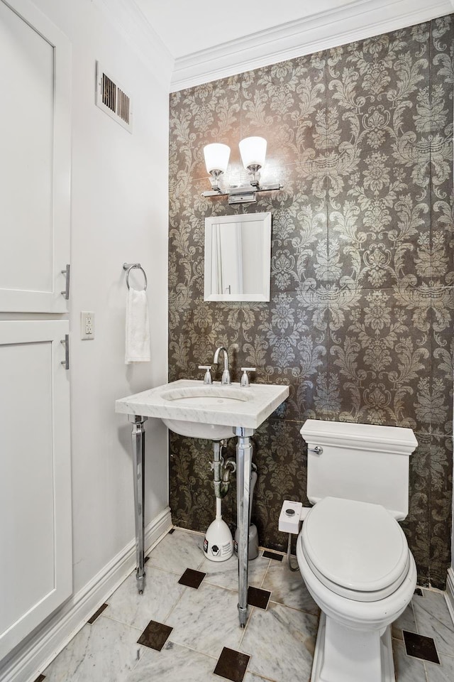 bathroom with visible vents, toilet, crown molding, wallpapered walls, and baseboards