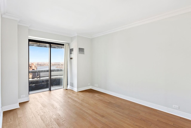 spare room featuring visible vents, crown molding, baseboards, and wood finished floors