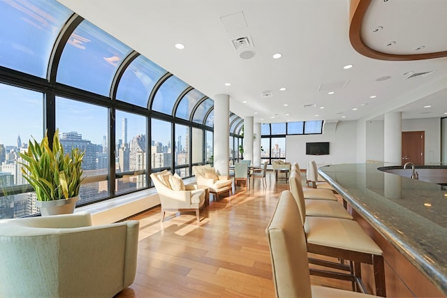 living room with a wealth of natural light, visible vents, a view of city, and light wood-type flooring