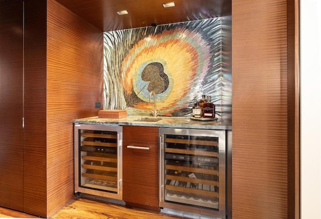 bar featuring wine cooler, light wood-type flooring, sink, and stone counters