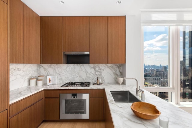 kitchen featuring light stone counters, sink, and appliances with stainless steel finishes