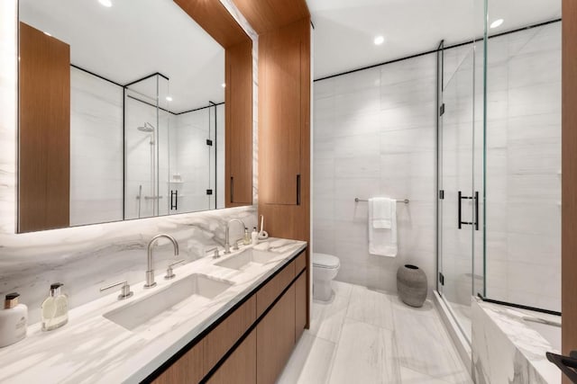 bathroom with a shower with shower door, vanity, tile walls, and toilet