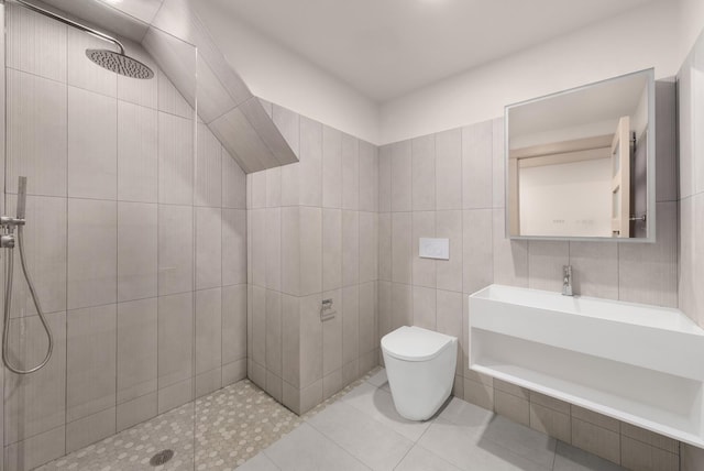 full bathroom featuring tile walls, toilet, tiled shower, tile patterned floors, and vanity