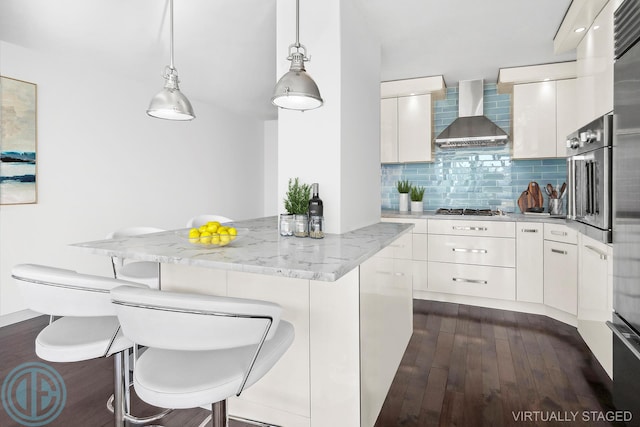 kitchen with stainless steel appliances, a kitchen island, wall chimney range hood, tasteful backsplash, and dark wood finished floors