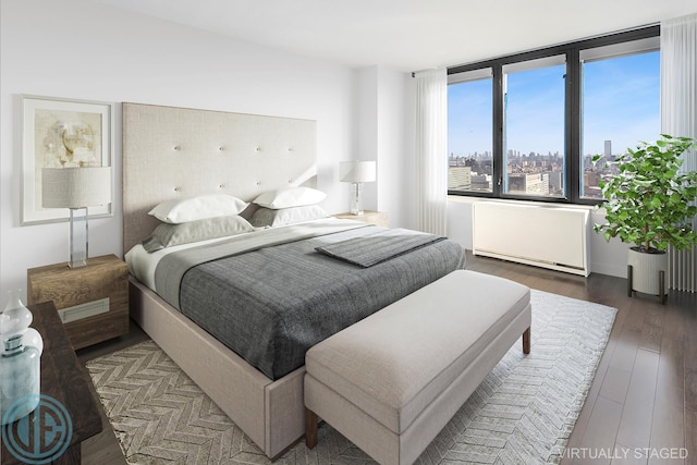 bedroom featuring radiator heating unit, a city view, and wood finished floors