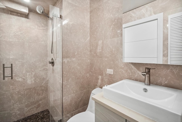 full bath featuring decorative backsplash, toilet, a tile shower, vanity, and tile walls