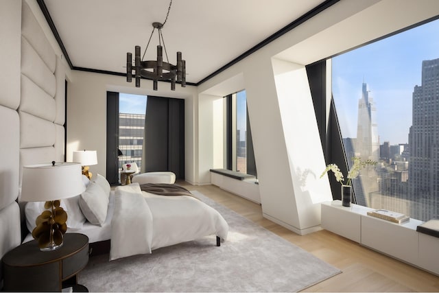 bedroom featuring a view of city, crown molding, light wood-type flooring, and an inviting chandelier