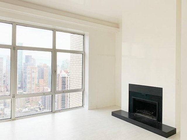 unfurnished living room featuring a fireplace with raised hearth and a city view