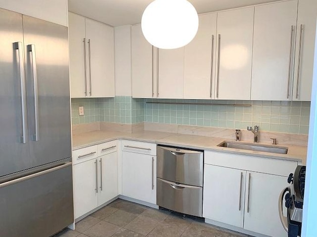 kitchen with stainless steel appliances, white cabinetry, a sink, and backsplash