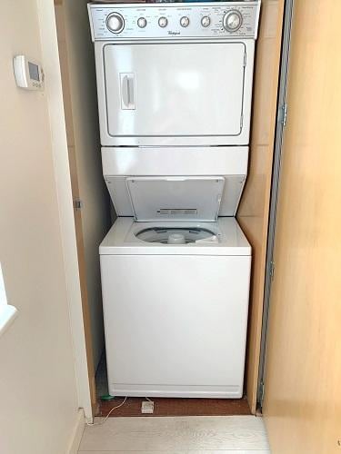 laundry room featuring stacked washing maching and dryer, baseboards, and laundry area