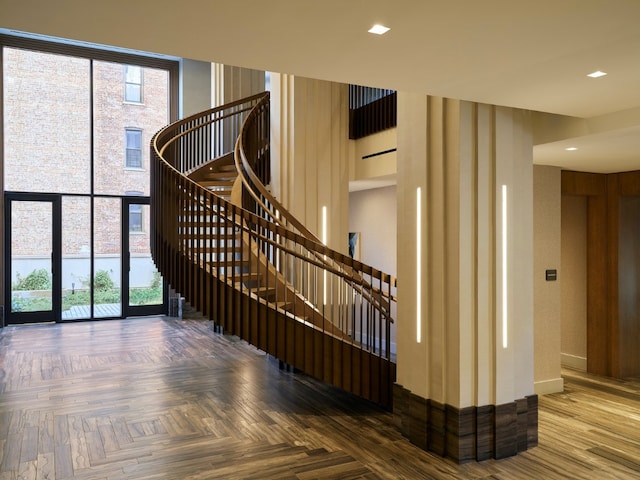 stairway with parquet floors, a towering ceiling, and expansive windows