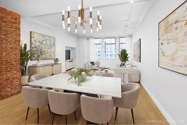 dining room with brick wall, a chandelier, ornamental molding, light hardwood / wood-style floors, and track lighting