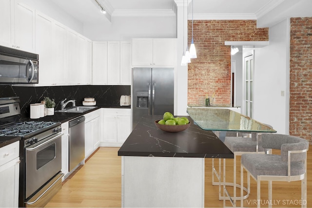 kitchen featuring ornamental molding, a sink, a center island, stainless steel appliances, and light wood-style floors