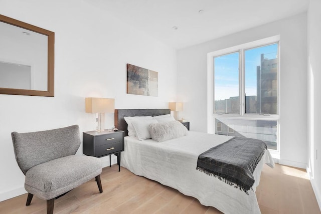 bedroom with light wood finished floors and baseboards