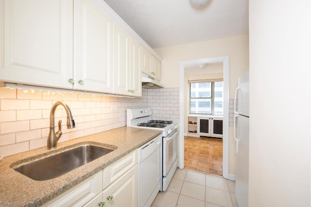 kitchen with white cabinetry, sink, white appliances, and light stone countertops