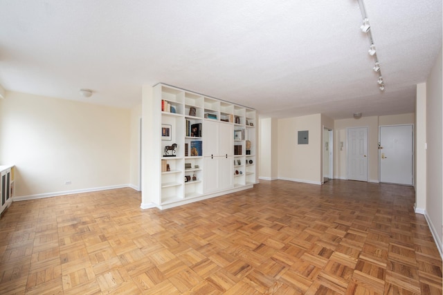 spare room with baseboards, a textured ceiling, and track lighting