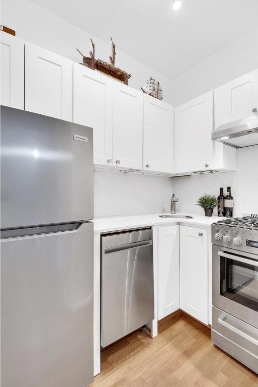 kitchen featuring white cabinets, light hardwood / wood-style floors, sink, and appliances with stainless steel finishes