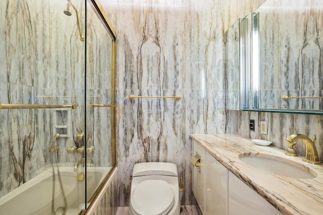 full bathroom featuring toilet, enclosed tub / shower combo, tile walls, and vanity