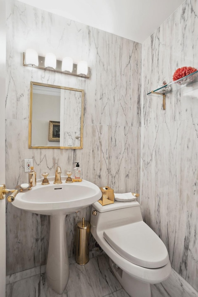 half bathroom featuring toilet and marble finish floor