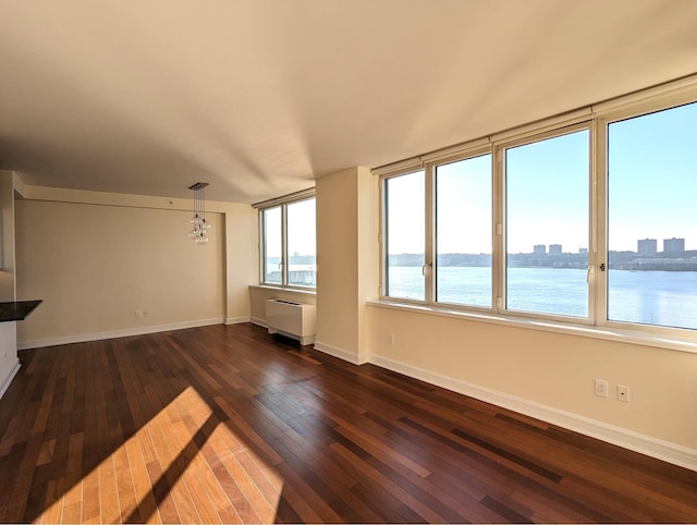 interior space with a notable chandelier, dark wood-style floors, baseboards, and a water view