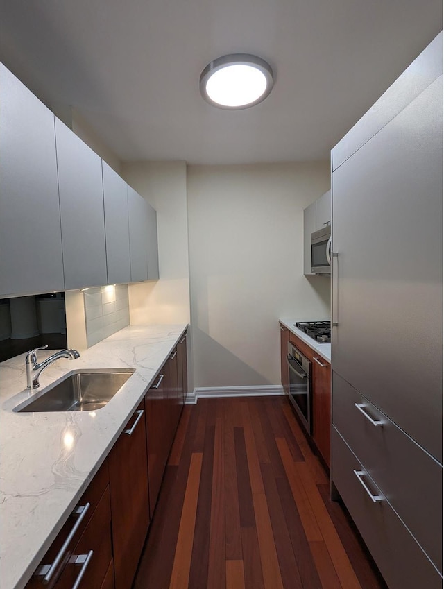 kitchen featuring a sink, modern cabinets, appliances with stainless steel finishes, and dark wood finished floors