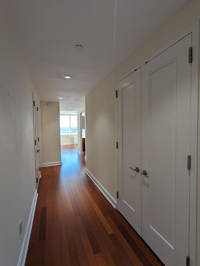 hallway featuring dark wood finished floors and baseboards