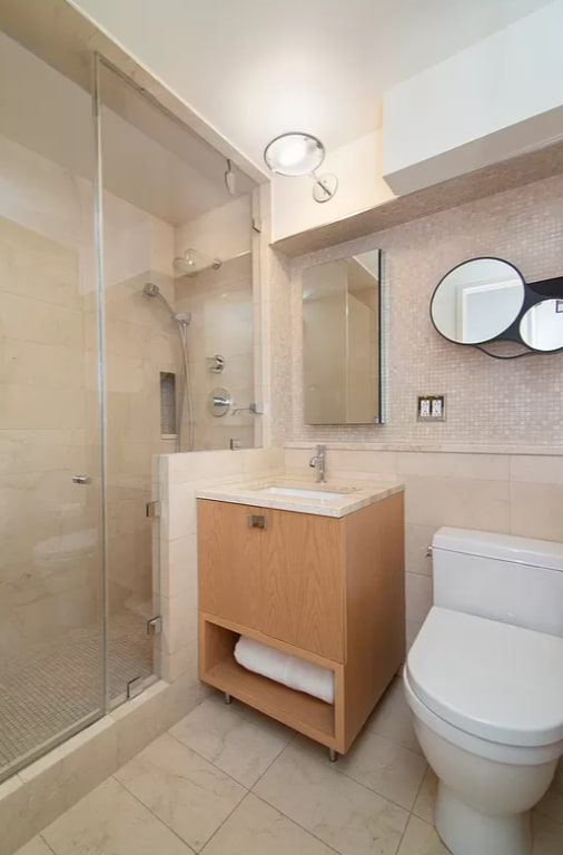 bathroom featuring toilet, tile walls, an enclosed shower, and vanity