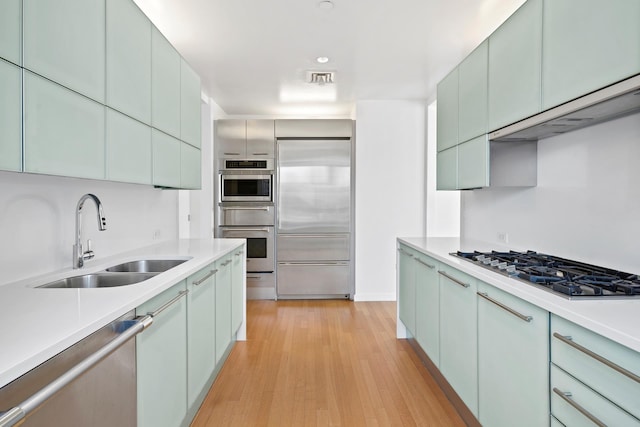 kitchen featuring light countertops, light wood-style flooring, appliances with stainless steel finishes, and a sink