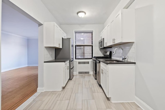 kitchen featuring white cabinets, radiator, appliances with stainless steel finishes, and sink